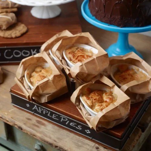 Four small apple pies in white ramekins and brown paper labeled Apple Pies at a Honey Salt Summerlin restaurant.