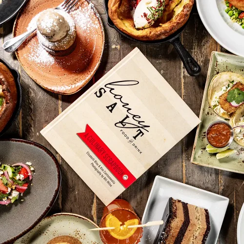 Overhead view of the Honey Salt Food and Drink Cookbook with some dishes from the book, at Honey Salt restaurant Las Vegas.